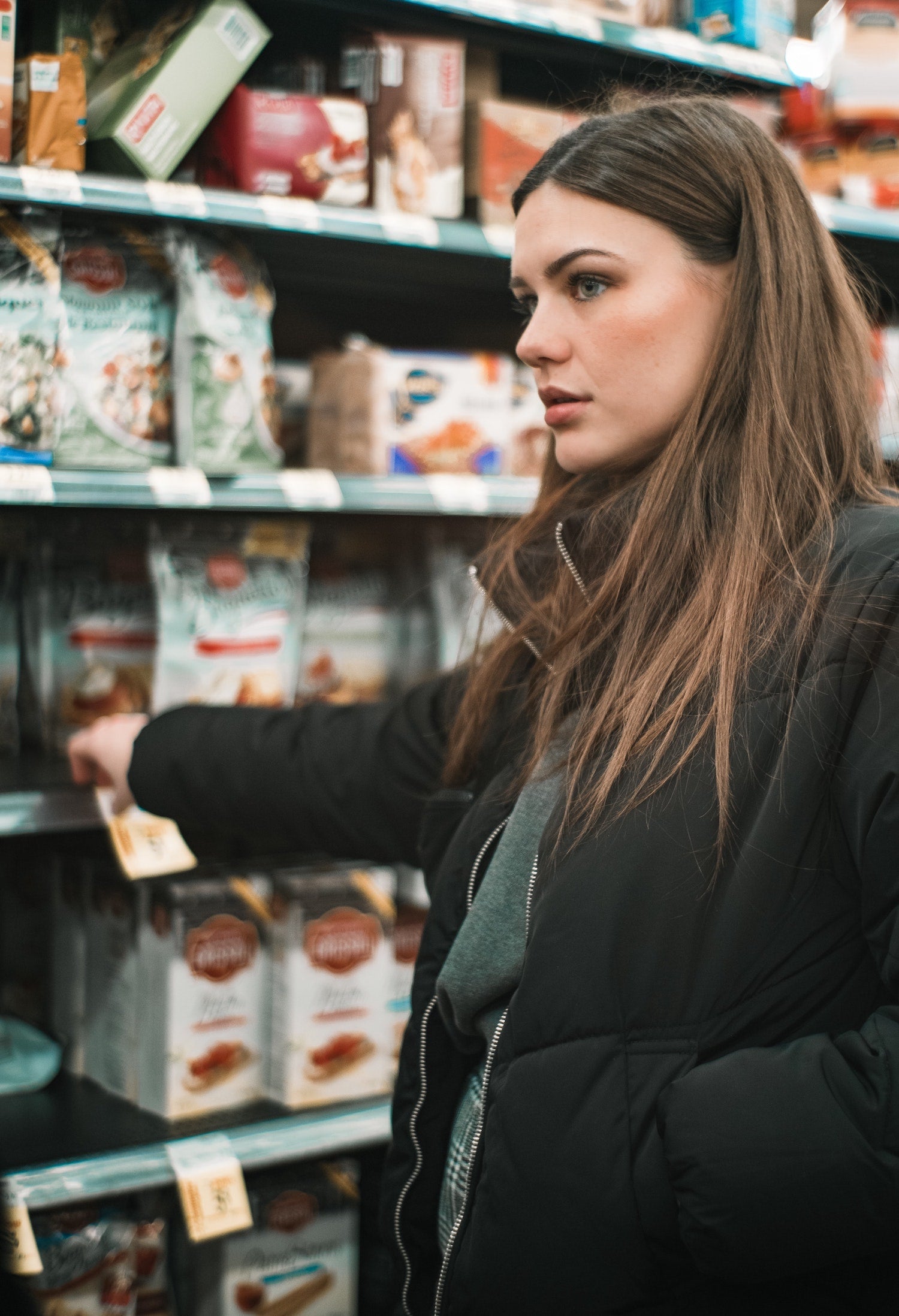 Woman looking concerned in aisle of a grocery store