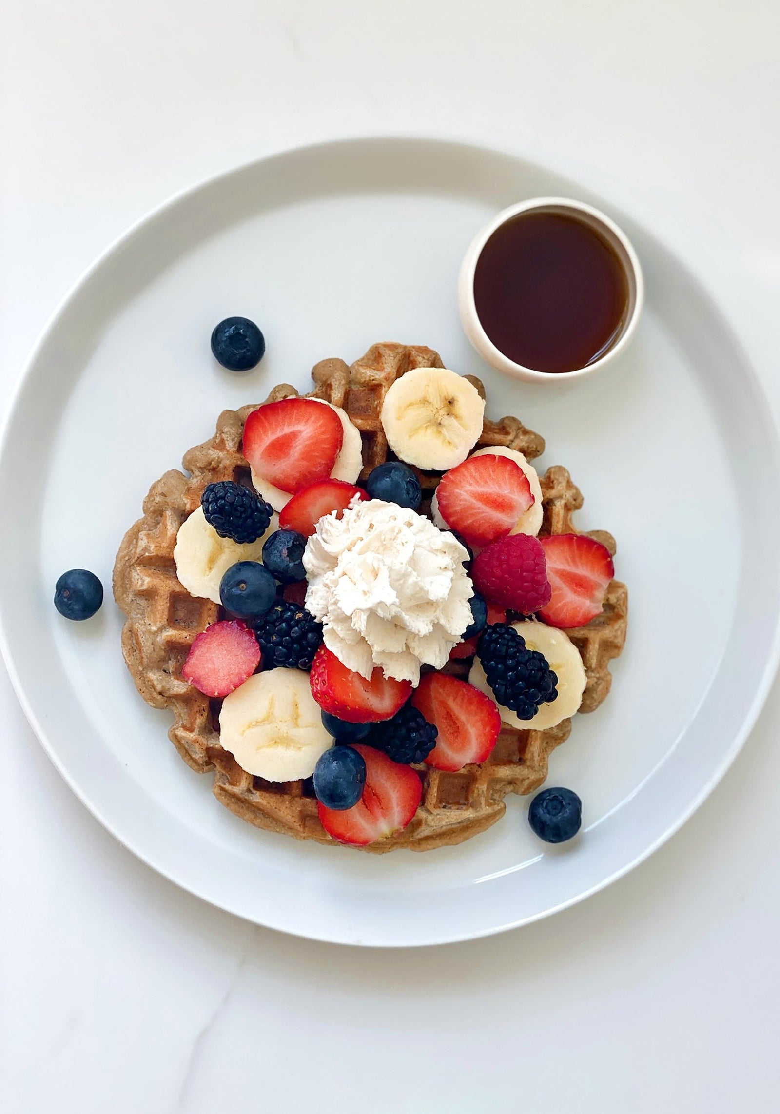 Gluten-free vegan buckwheat waffle with whipped cream and fresh berries
