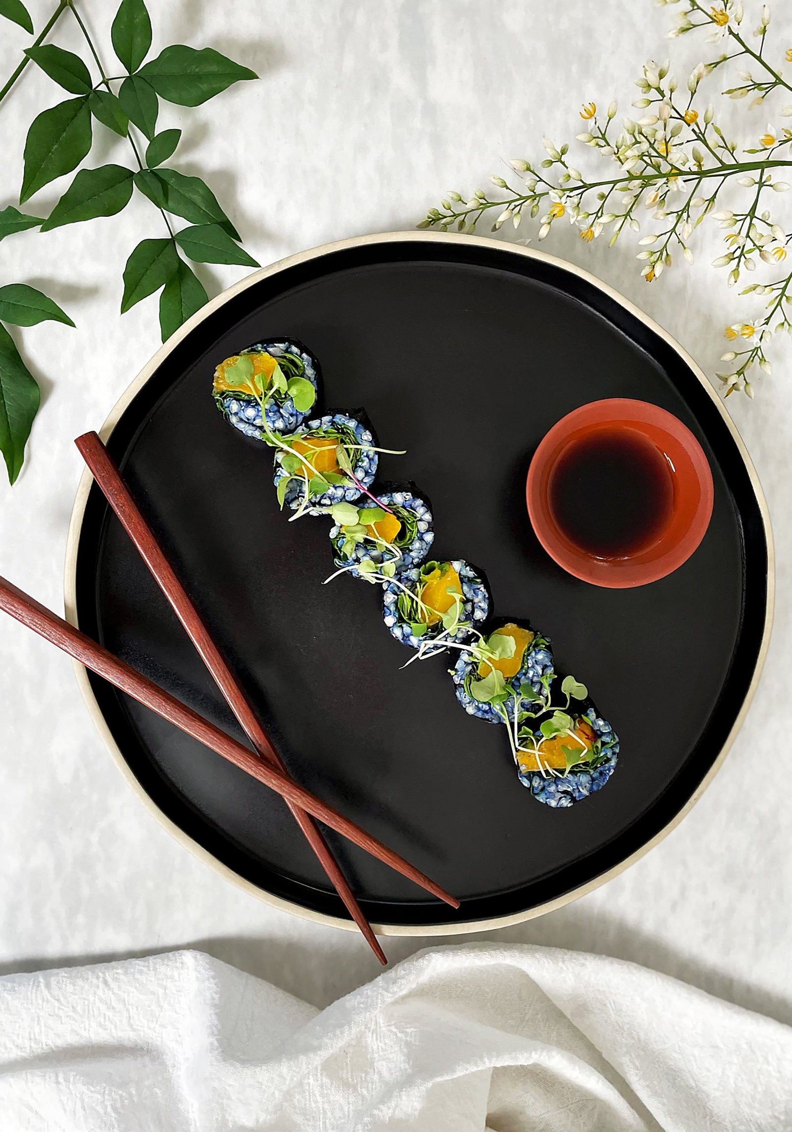 Veggie sushi rolls with buckwheat lined up on black plate
