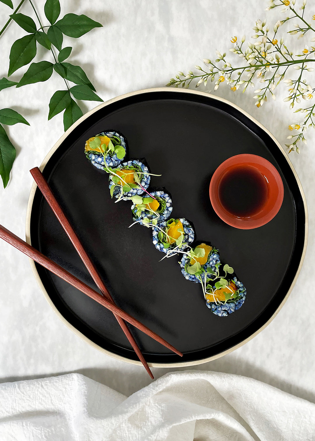 Veggie sushi rolls with buckwheat lined up on black plate