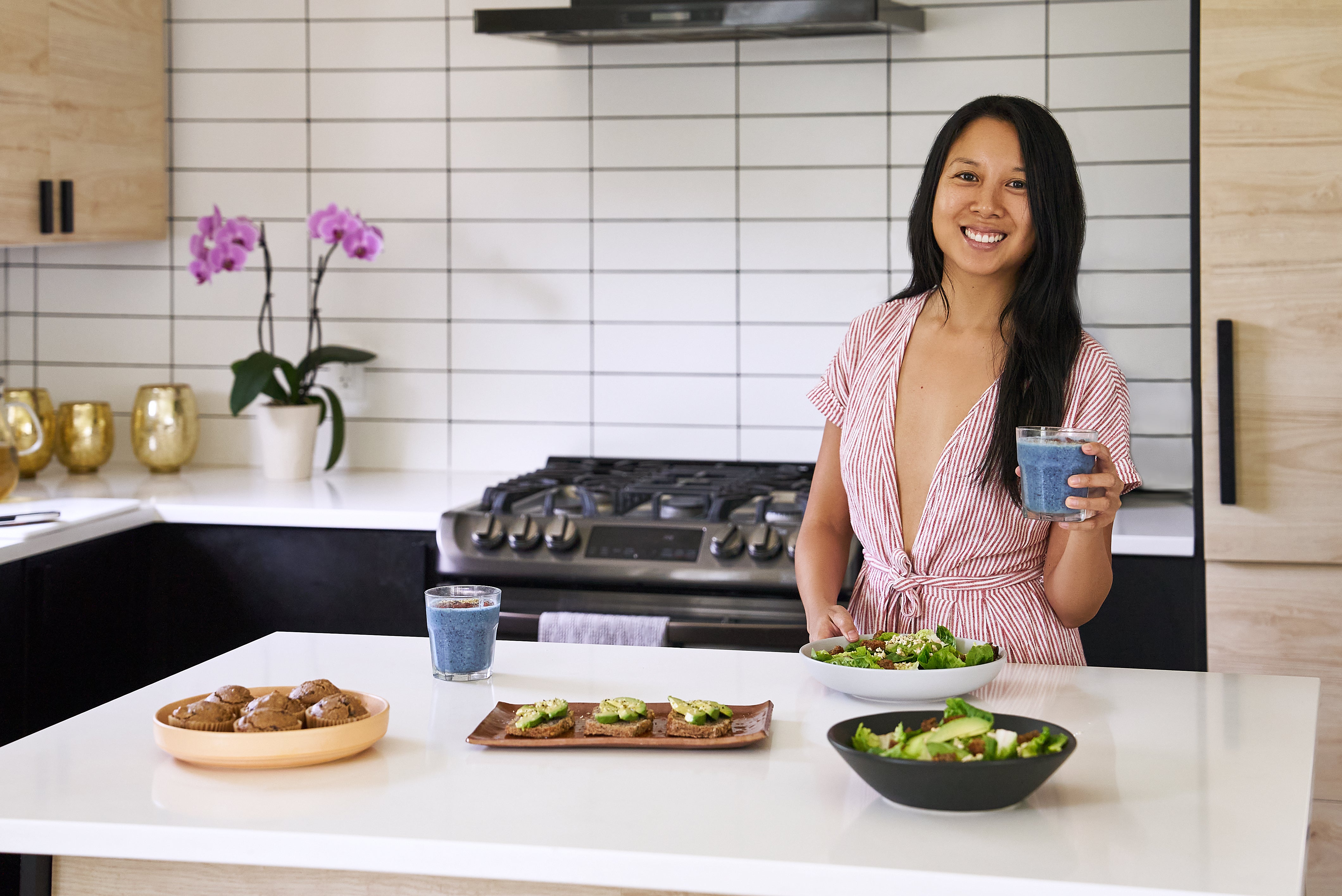 Founder and author holding blue smoothie by kitchen island with buckwheat groats recipes