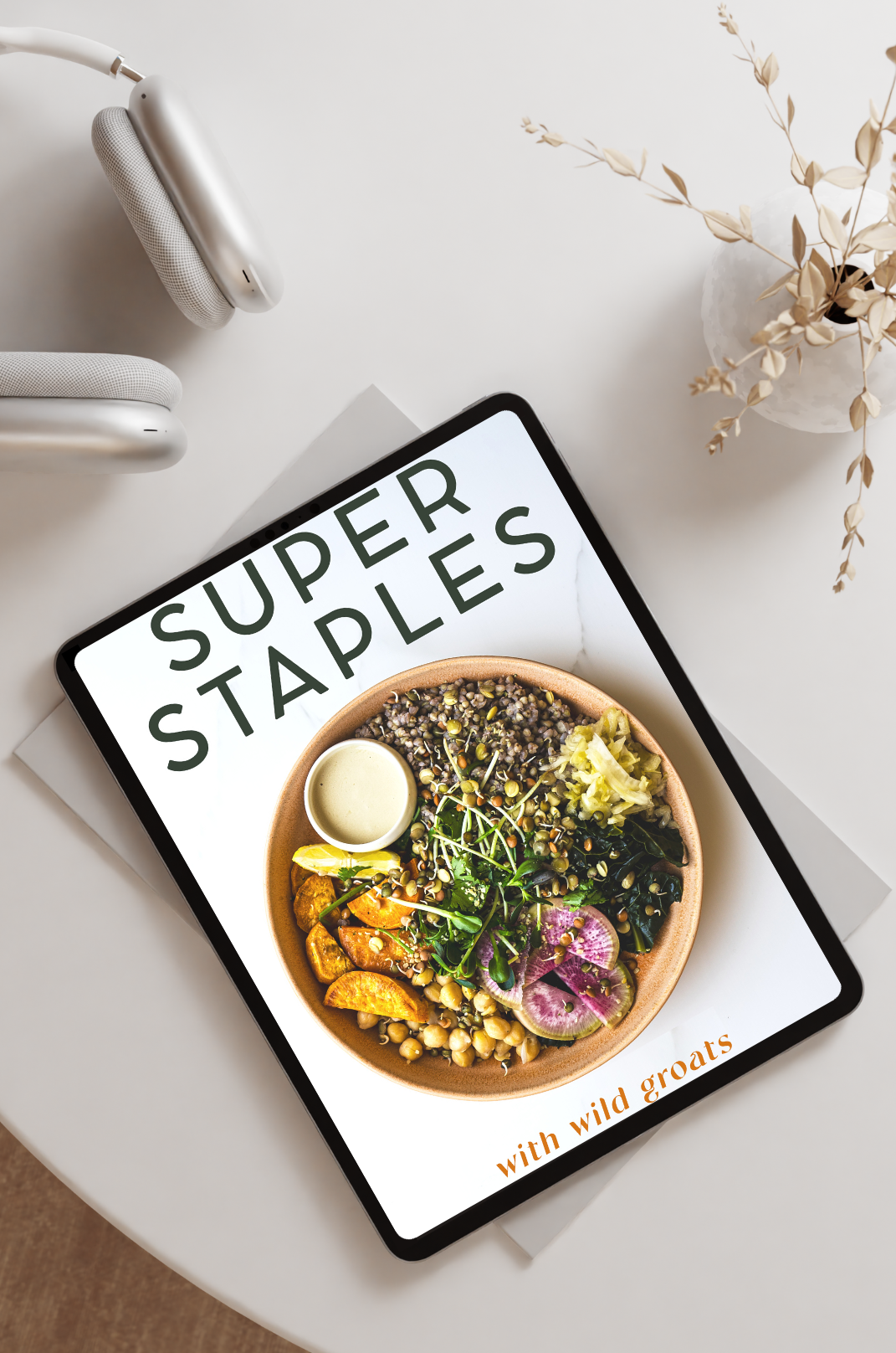 Super Staples recipe ebook displayed on iPad with white headphones on desk